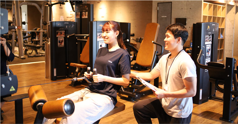 トレーナーに教わりながら胸のトレーニングをしている様子の画像